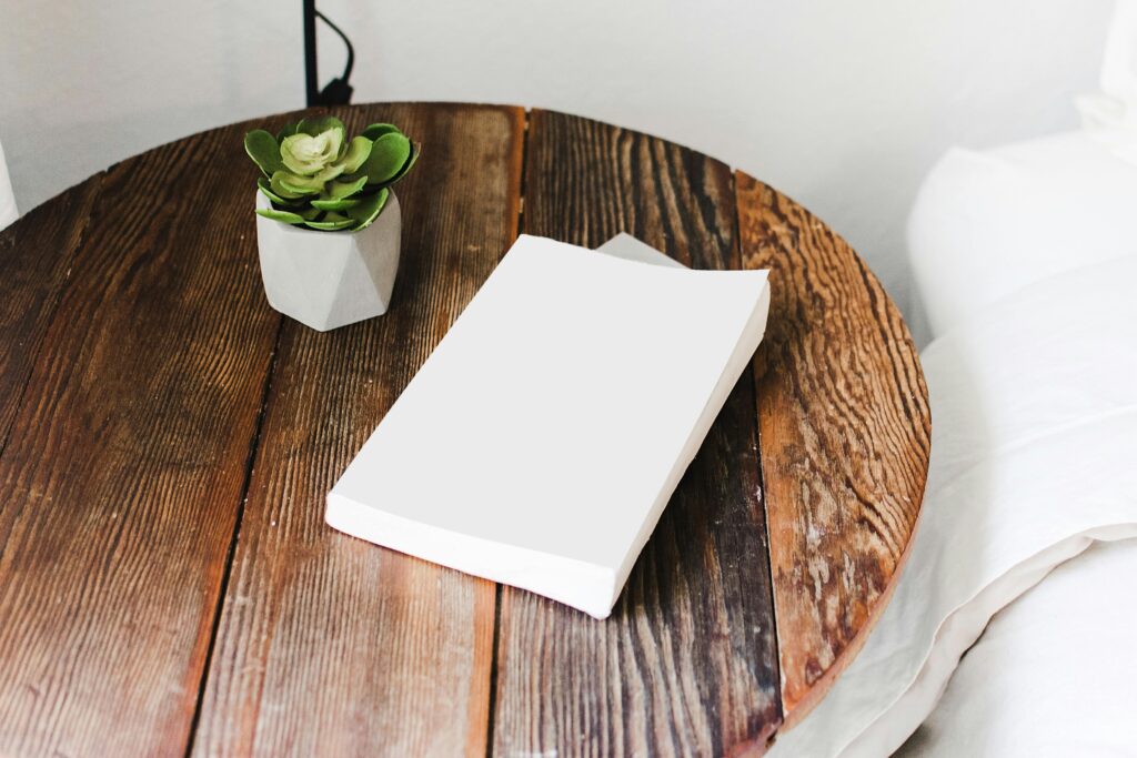 Close-up of a wooden bedside table with a succulent plant and a book, showcasing cozy home decor.